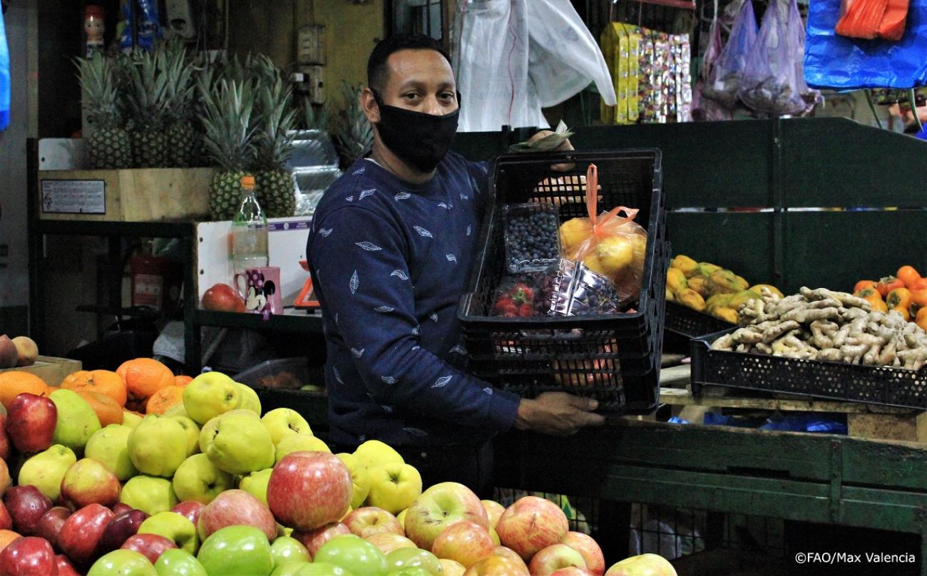 hombre en mercado de frutas con mascarilla